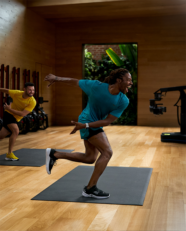 Apple Fitness+ 教練在影片工作室的攝影機前主持課程。 