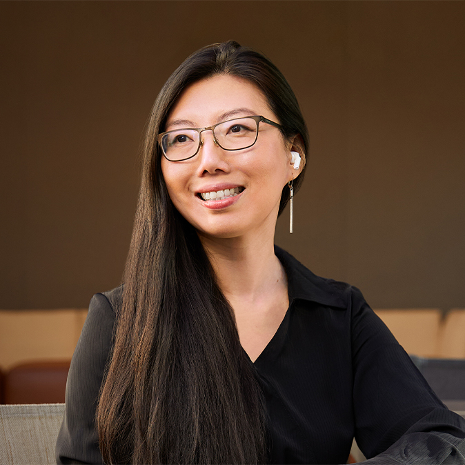 Jessica 坐在戶外，微笑望向右邊，背景是辦公區域。