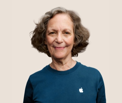 Portret van een glimlachende Apple Retail-medewerker met golvend donkergrijs haar.