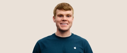 Portret van een lachende Apple Retail-medewerker met kort donkerblond haar.