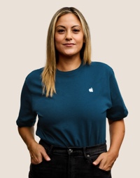 Portret van een glimlachende Apple Retail-medewerker met lang donkerblond haar.