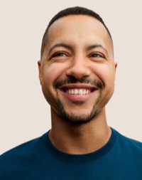 Portret van een glimlachende Apple Retail-medewerker met kort donker haar en een baard.