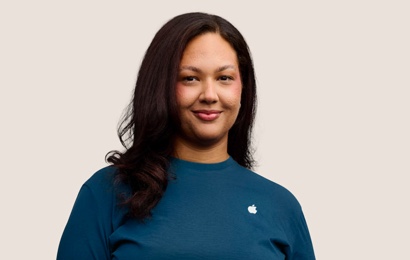 Portret van een glimlachende Apple Retail-medewerker met lang donker haar.