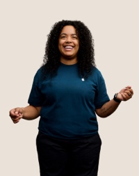 Portret van een lachende Apple Retail-medewerker met lange, donkere krullen.