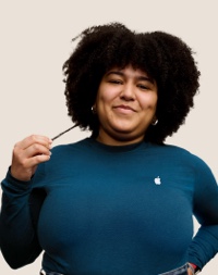 Portret van een lachende Apple Retail-medewerker met lange, donkere krullen.