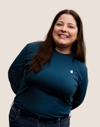 Portret van een glimlachende Apple Retail-medewerker met lang donker haar.
