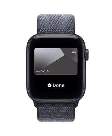 Apple Watch SE 3 med urkasse av aluminium i midnatt og Sport Loop i ankerblå viser Apple Pay i Lommebok-appen. På høyre side av urkassen vises Digital Crown.