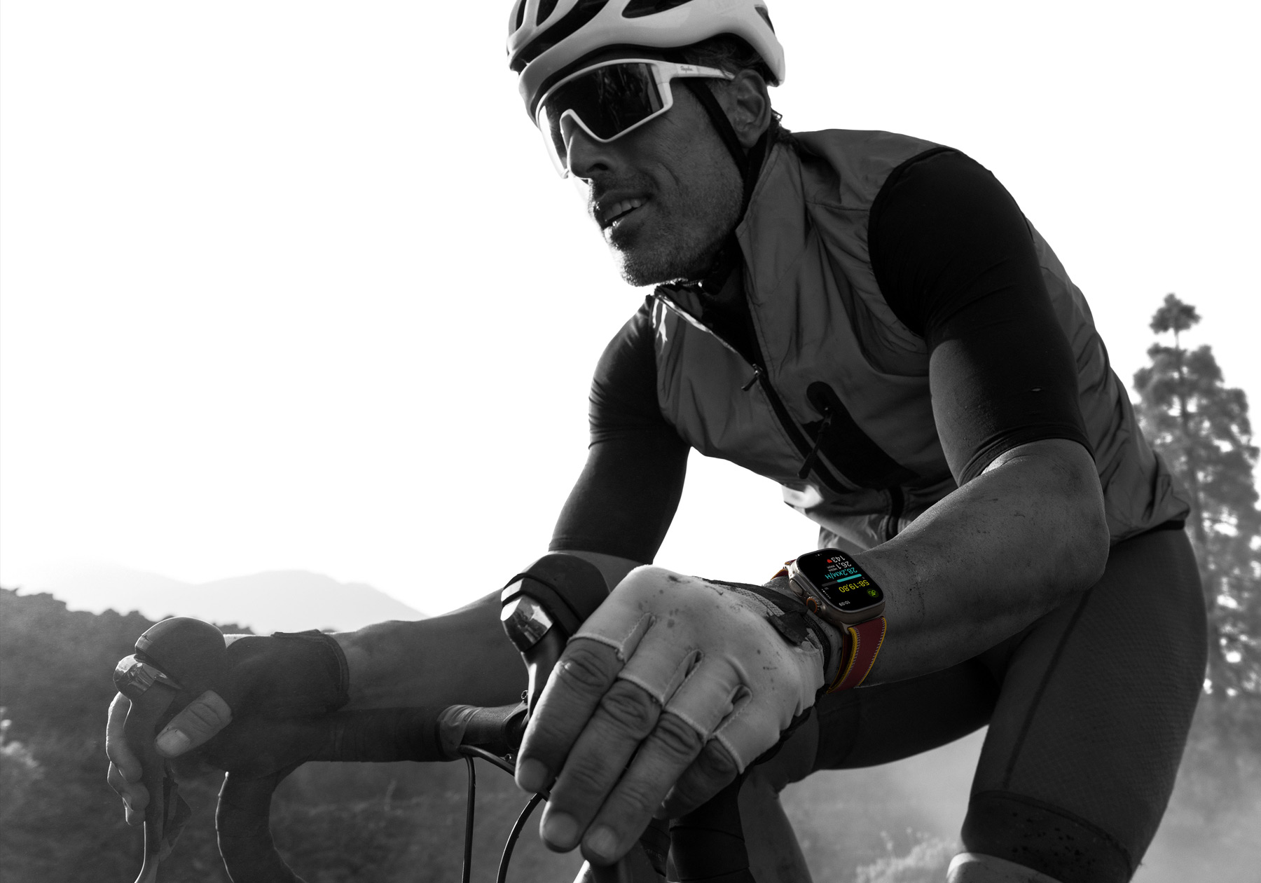 A person riding a road bike while wearing Apple Watch Ultra 4, screen shows cycling metrics