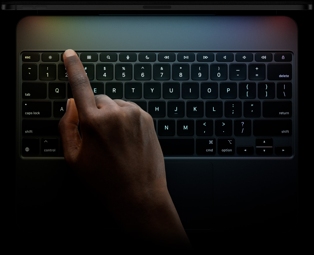 iPad Pro, orientation paysage, noir sidéral, profil du bord supérieur, fixé à un Magic Keyboard, face avant, orientation paysage, touches rétroéclairées noires, rangée de touches de fonction dédiée, Echap, Tabulation, Verrouillage Majuscule, Maj, Control, Option, Maj, Supprimer, Retour Arrière, touches fléchées avec inversion du T, trackpad intégré